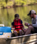 Ready Set Fish 3 Tray Tackle Box With Starter Tackle Kit on boat with aqua blue lid, tan base, beside angler