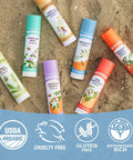 Must Have Organic Lip Balm Gift Set Four Flavor Pack Featuring Tangerine Lavender Orange Vanilla Grapefruit Silky Long Lasting Moisturizer For Dry Lips With All Natural Beeswax Olive Oil And Aloe tubes on sand