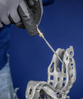 Person using Diamond Needle File Set 5 Piece D126 Grit 5.5 Inch for finishing metal part with gloves in blue background.