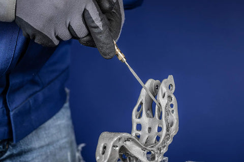 Person using Diamond Needle File Set 5 Piece D126 Grit 5.5 Inch for finishing metal part with gloves in blue background.