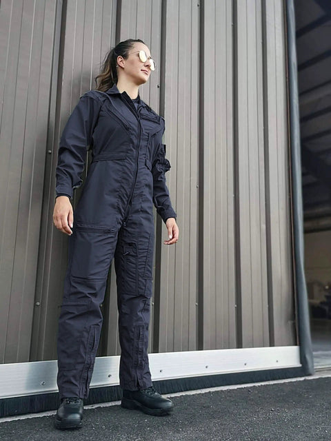 Heavy Duty Poly Cotton Twill Coverall In Dark Navy With Alpha Fit Snag Resistant Trims worn by a woman near a garage wall.