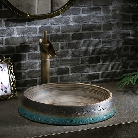 Bathroom Vessel Sink Vintage Hand Engraving Skirted Vessel, Ceramic Round Sink on a stone countertop with faucet.