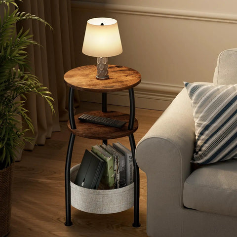 3 Tier Round Side Table With Storage Basket 24 Inch Tall Rustic Brown Space Saving End Table beside sofa with lamp and books
