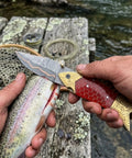 Using Handmade Copper Damascus Folding Knife With Ladder Pattern Blade Brass Engraved Red Resin Handle on fish by river