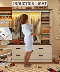 Woman using 4 Door Armoire Wardrobe With Sliding Barn Doors LED Lighting Drawers And Hanging Rod Freestanding Wooden Closet In Antique White Finish For Bedroom Storage