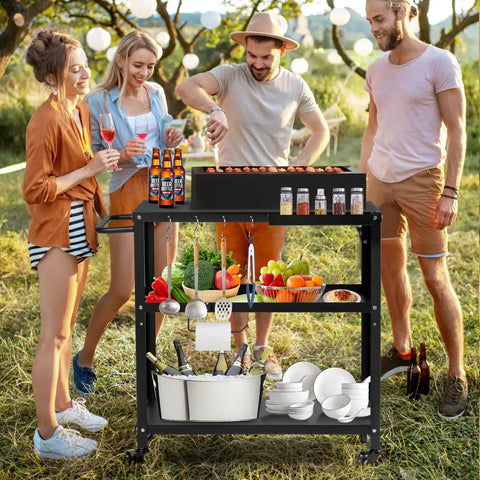 Four people enjoying outdoor cooking with Outdoor Grill Cart Table With Pizza Oven Stand For Indoor And Outdoor Cooking 4 Locking Casters Side Handle Hooks Spice Caddy Paper Towel Holder Large Prep Surface Heavy Duty Black in a garden setting.