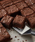 Close-up of mini stainless steel spatula beside brownie squares on a baking sheet.