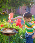 38-Inch Freestanding Outdoor Bird Bath With Detachable Feeder Bowl in use by child, vintage bronze finish in garden setting