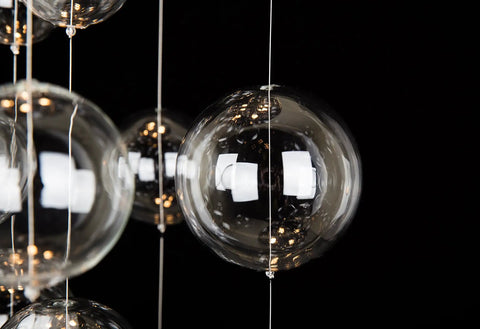 Close-up of the Five-Light Modern Crystal Chandelier with Spiral Raindrop Style Pendant light globe in focus against a black background.