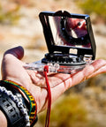 Person holding Advanced Mirror Compass For Pros And Serious Hikers With Metric UTM Scales And Inch Ruler in outdoor setting