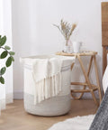 Large Rope Laundry Basket With Handles, Modern Woven Storage Bin In Light Gray, 18x16 inches, beside a bedside table in bedroom.
