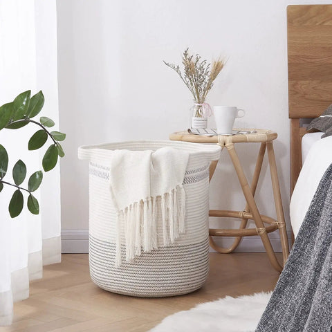 Large Rope Laundry Basket With Handles, Modern Woven Storage Bin In Light Gray, 18x16 inches, beside a bedside table in bedroom.