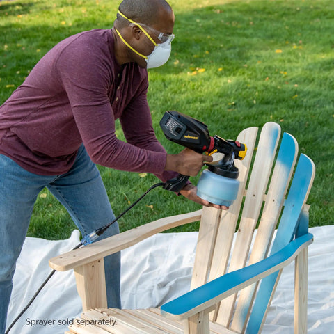 Person using iSpray Front End Nozzle for HVLP Sprayers for even coating on wooden chair outdoors.