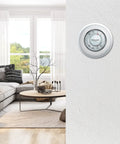 Round Heat Only Manual Thermostat Large White Easy Install Mercury Free Precise Temperature Control Plus Minus One Degree F Classic Wall Mounted Thermostat With Decorative Cover Ring shown in modern living room setting with sofa and coffee table