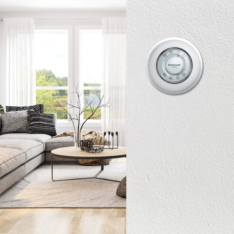 Round Heat Only Manual Thermostat Large White Easy Install Mercury Free Precise Temperature Control Plus Minus One Degree F Classic Wall Mounted Thermostat With Decorative Cover Ring shown in modern living room setting with sofa and coffee table