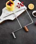 Top Shelf Cheese Slicer Kit With Kickass Stainless Steel Wires And Slick Wood Handles Plus Assembly Hex Key And Replacement Parts For Nifty DIY Cheese Board Crafting Sets displayed on a marble board.