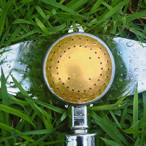 Close-up of 360 Degree Metal Spot Sprinkler For Small Gardens And Lawns on grass, showing durable yellow metal sprinkler head.