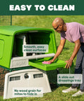 Man cleaning large green plastic chicken coop for easy cleaning and a secure hen house, showing slide-out droppings tray.