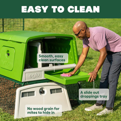 Man cleaning large green plastic chicken coop for easy cleaning and a secure hen house, showing slide-out droppings tray.