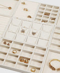 Totally Sweet Beige Linen Jewelry Display Tray With Sixteen Grid Slots For Rings Necklaces And Bracelets Ultra Soft Fabric Organizer showcasing various compartments filled with rings and earrings.