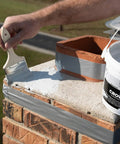 Applying Bone Dry Chimney Crown Sealer Brushable Elastomeric Waterproof Membrane on chimney top with a brush.