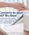 Hand pressing ADT Blu Base security device for synchronizing home security systems with cellular backup.
