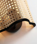 Close-up of Mid Century Bohemian Wall Sconce Lamp with Rattan Shade and Velvet Rim, cozy ambient lighting, beige color.