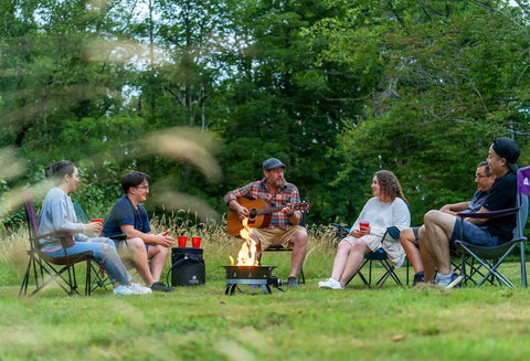 Group enjoying Go-To Portable Propane Fire Pit 19-Inch Smokeless Gas Firebowl With 58,000 BTU in a lush outdoor setting.