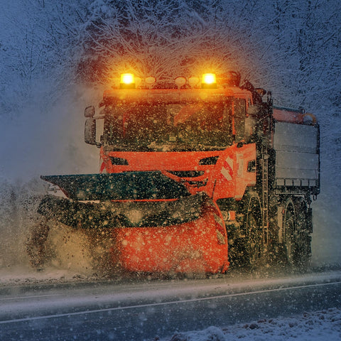 Magnetic cordless beacon lights on orange snowplow truck cab, front view with two amber strobes.