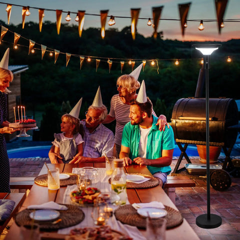 Solar Powered Outdoor Floor Lamp for Patio and Garden in family gathering scene, with party hats and dinner setup