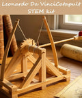 Leonardo Da Vinci Catapult Kit Build a Working Wooden Siege Engine on a table with plans and books in the background.