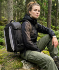 Person outdoors with black TSA Friendly Carry On Travel Backpack for Men and Women With 180 Degree Full Opening Waterproof Pocket.