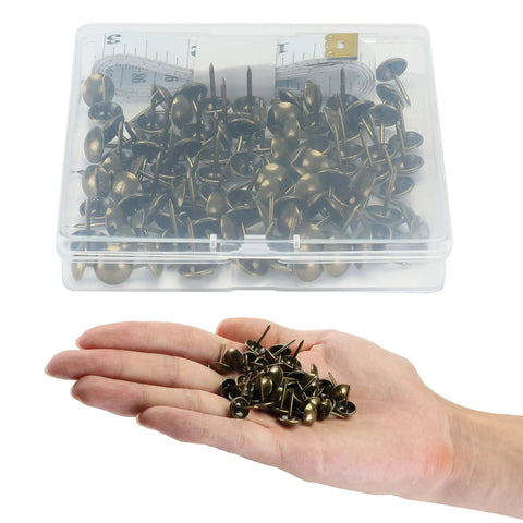 Hand holding Bronze Upholstery Tacks 100 Pack Decorative Nail Heads for Furniture, Antique Brass Finish with measuring tape in box