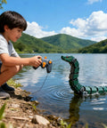 Child playing by lake with green remote-controlled sea serpent toy