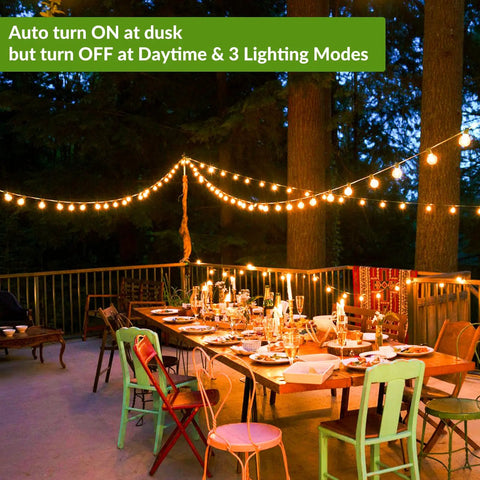 Outdoor evening setup with 100Ft Solar String Lights With 52 LED Globe Bulbs, Warm 2700K Glow, over a table on a patio.