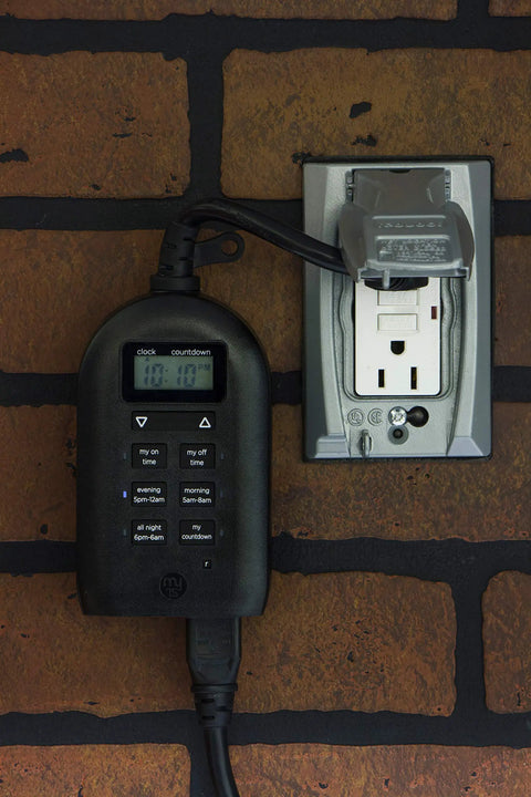 Weatherproof Digital Plug In Timer With Dual Outlets Indoor Outdoor Ready Custom On Off Presets 24 Hour Countdown Ideal For Landscape Lighting Patio Lights And Seasonal Appliances attached to brick wall.