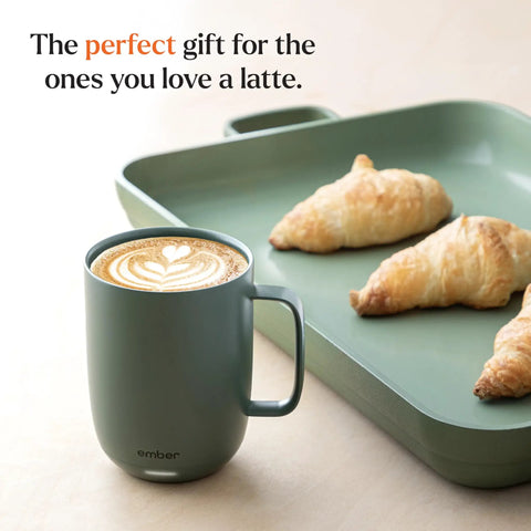 Keep Your Coffee Piping Hot With This App Controlled Smart Mug Featuring A 14Oz Rechargeable Heated Warmer in sage green with latte art.
