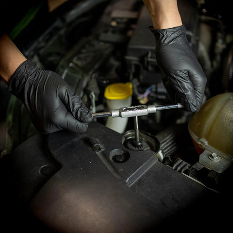 Mechanic using Beast 110 Piece Metric Tap And Die Set for threading bolts on an engine with gloved hands