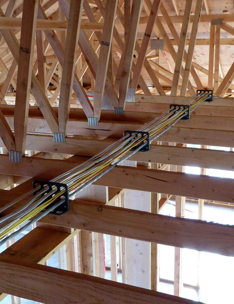 Box Of Fifty H2 Homer Helpers For Electrical Wire Management holding organized wires against wooden beams during construction.