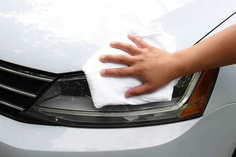 Hand wiping car headlight with Bulk 10 Lb White Cotton T Shirt Rags For Painting Stains Grease Cleaning In The Shop Or Auto Use Quick Dry Low Lint
