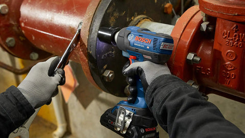 Worker using 18V EC Brushless Half Inch Impact Wrench with Friction Ring and Through Hole Bare Tool on metal pipe flange
