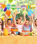 Birthday party scene with colorful hot air balloon cutouts set for classroom decor 36 pieces in 9 designs with glue dots.
