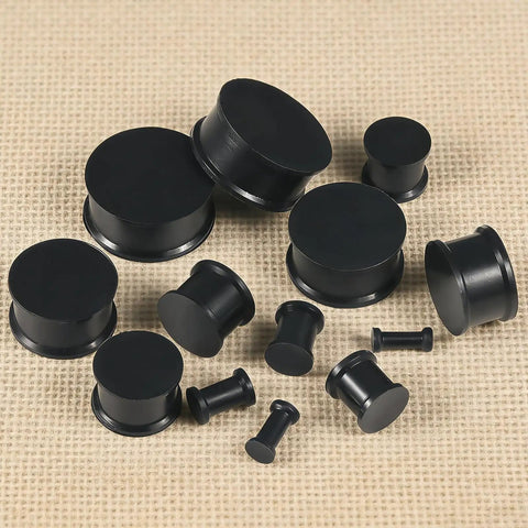 Soft Silicone Ear Gauges Set 8G To 25mm Stretching Kit For Women Men Black Flexible Plugs And Tunnels on beige background