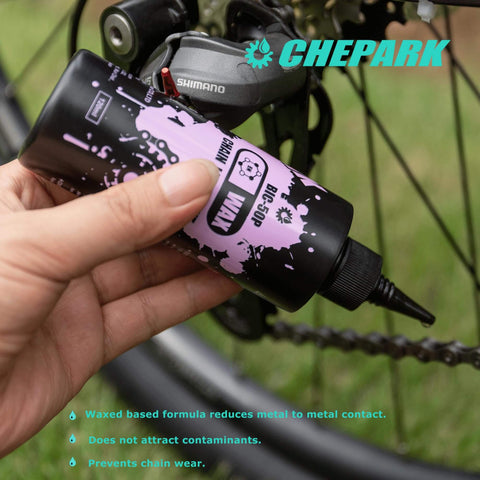 Hand holding bike lube with bicycle in background, part of Drivetrain Cleaning And Lubrication Essentials Kit With Bicycle Degreaser And Lubricant Brush Tool