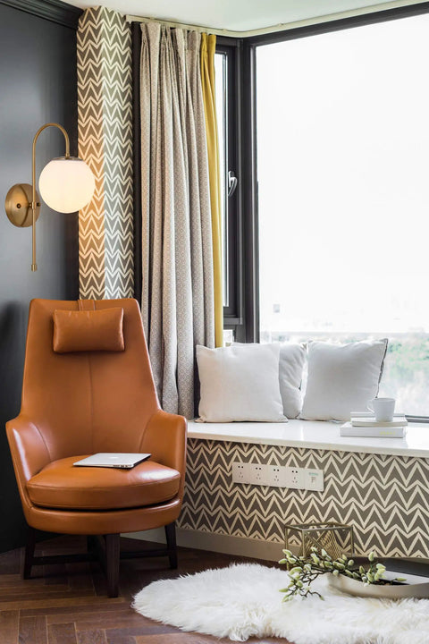 Gold Wall Sconce LED Globe Frosted Glass Shade Modern Bedside Light Fixture for living room with brown chair and window nook.