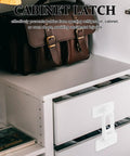 Four Pack Cabinet And Oven Door Safety Locks for childproofing on white drawer with brown leather bag on top
