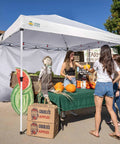 SunWall Silver Coated Sidewall For 10x10 Pop Up Canopy Tent 1 Pack Waterproof 150D Polyester With UPF50 Plus UV Protection White Ideal For Hangouts And Weatherproof Shade On Most 10x10 Straight Leg Canopies used at a farmers' market with a table of produce.