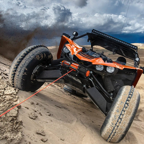 4500 Lb Waterproof Electric Winch with Wireless Remote pulling an off-road vehicle in sandy terrain