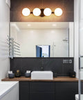 Sleek Matte Black Four Light Vanity Light Fixture With Opal Glass Globes above bathroom mirror, modern decor
