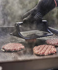Heavy Duty Weber Griddle Press For Perfect Bacon, Smash Burgers And Crispy Paninis pressing burger patties on a hot griddle.